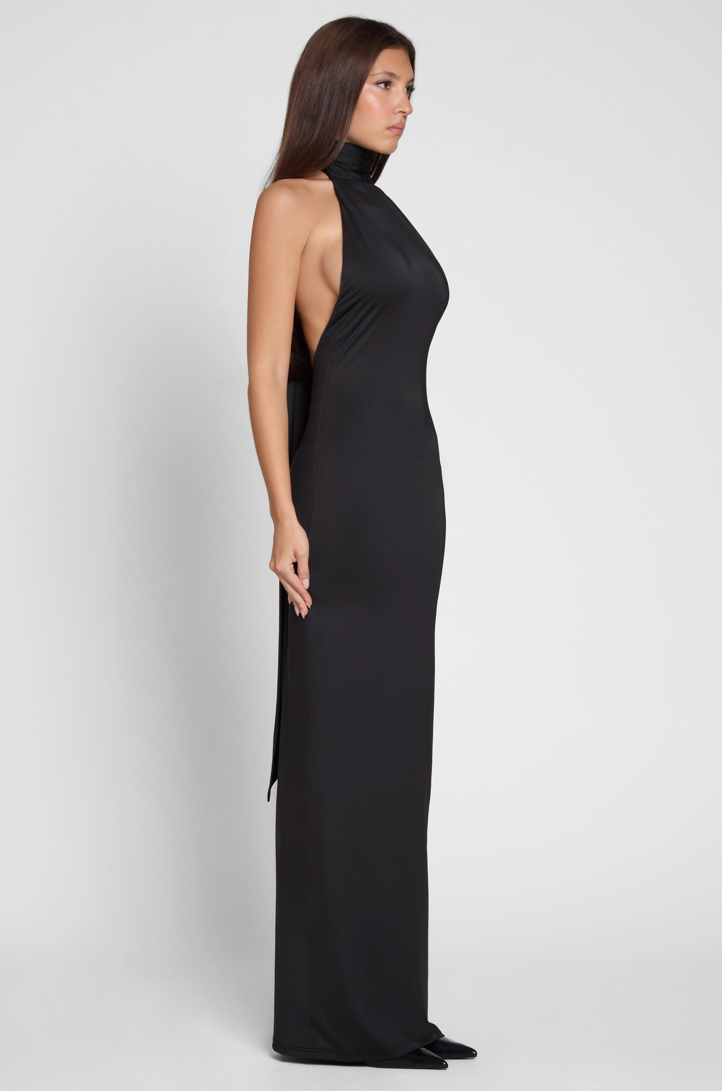 Model is wearing Alaia Drape Maxi Dress Black, side view.