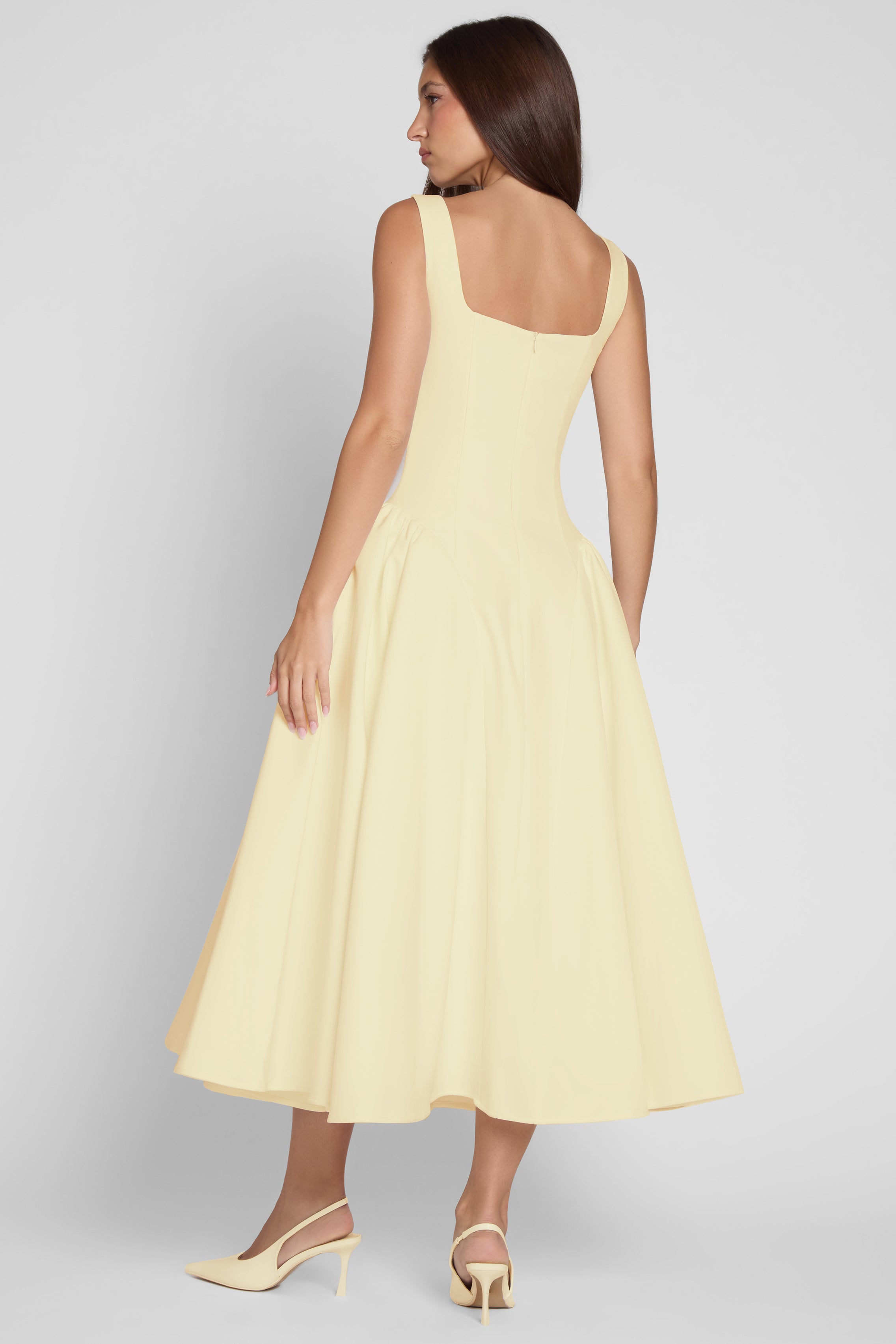Model is wearing Chloe Corset Midi Dress Yellow, back view.