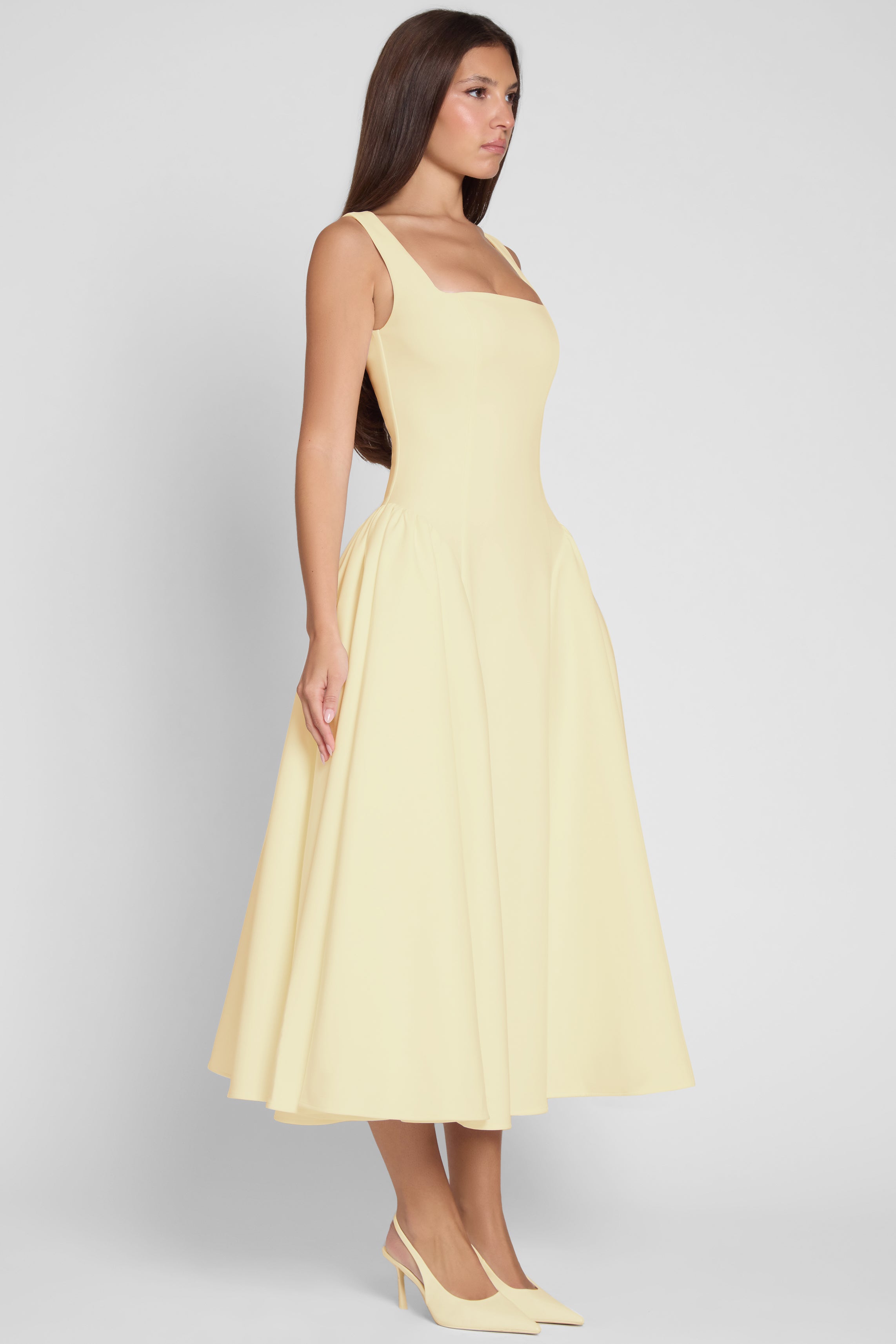 Model is wearing Chloe Corset Midi Dress Yellow, side view.