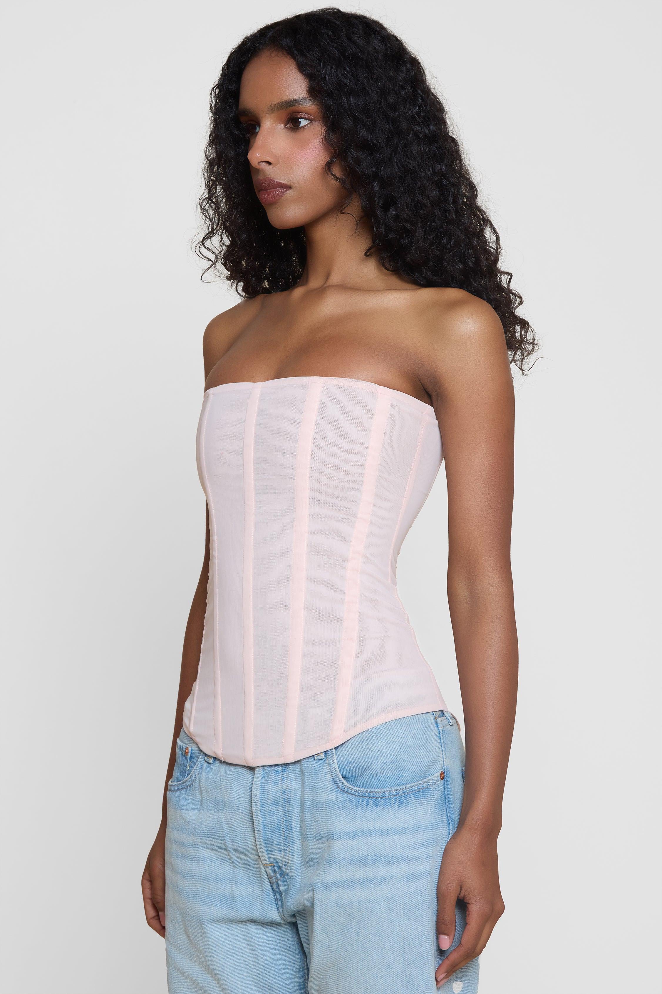 Model wearing Muse Mesh Corset Top in Pink, side view.
