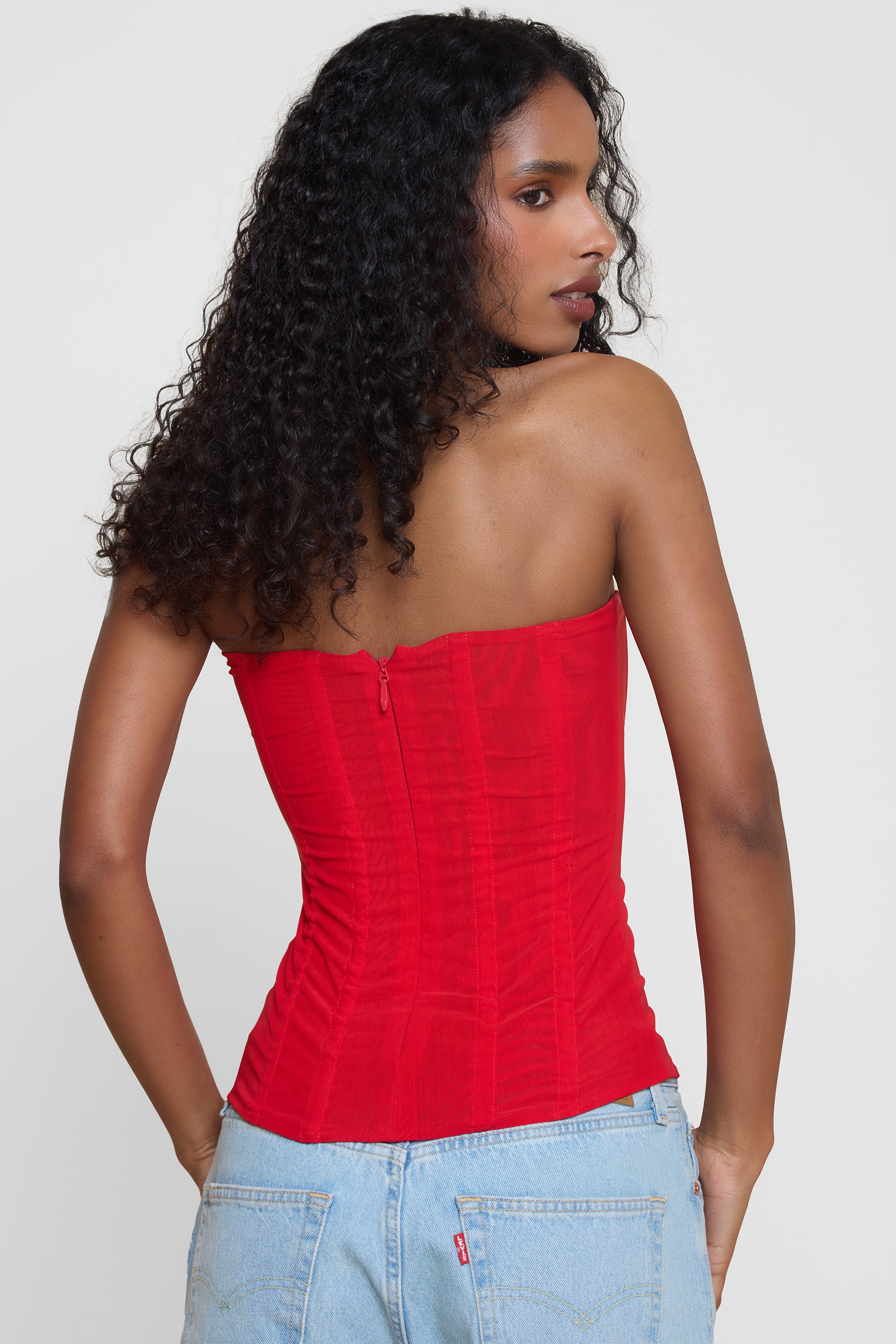 Model wearing Muse Mesh Corset Top in Red, back view.