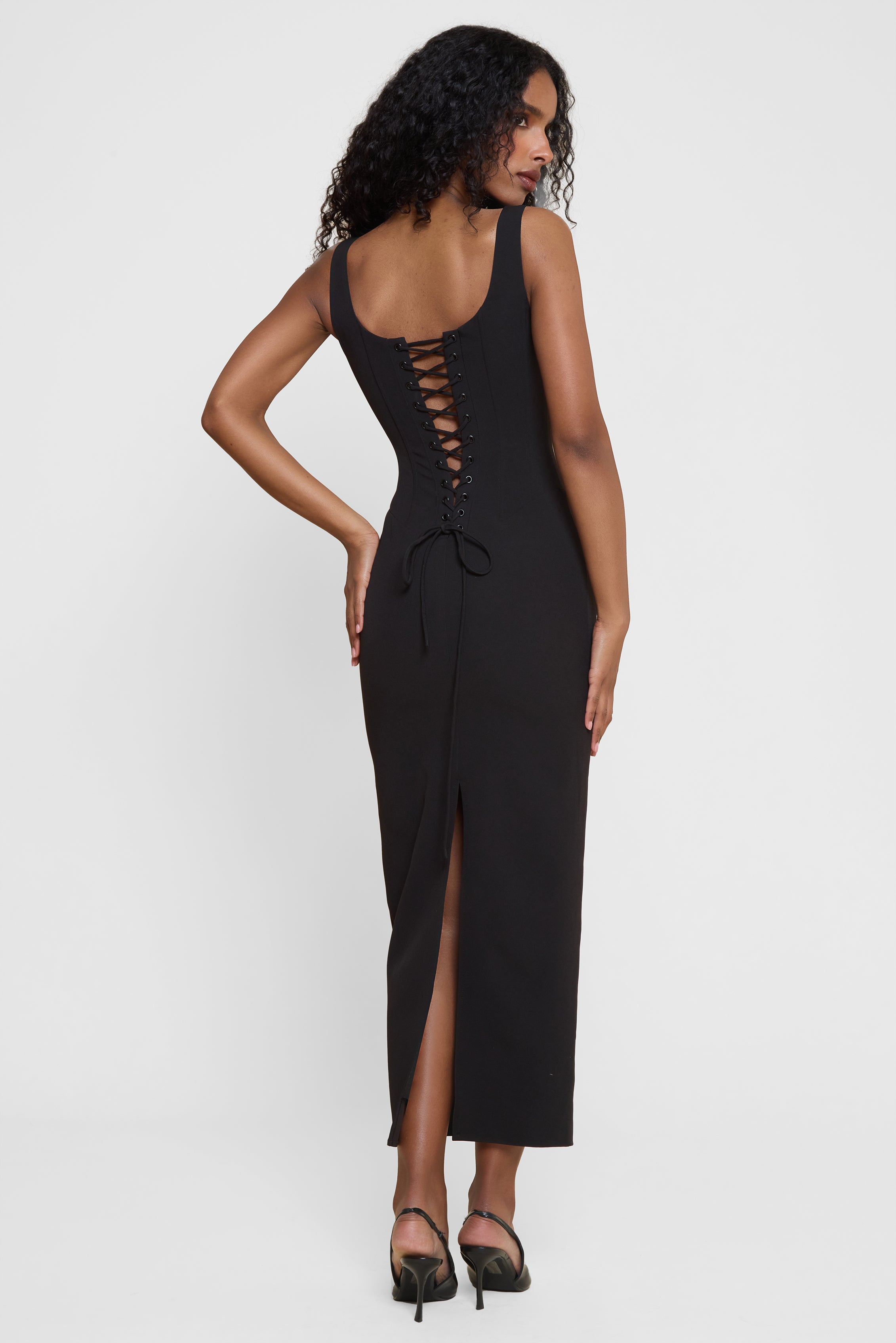 Model wearing Sancia Corset Midi Dress in Black, back view.