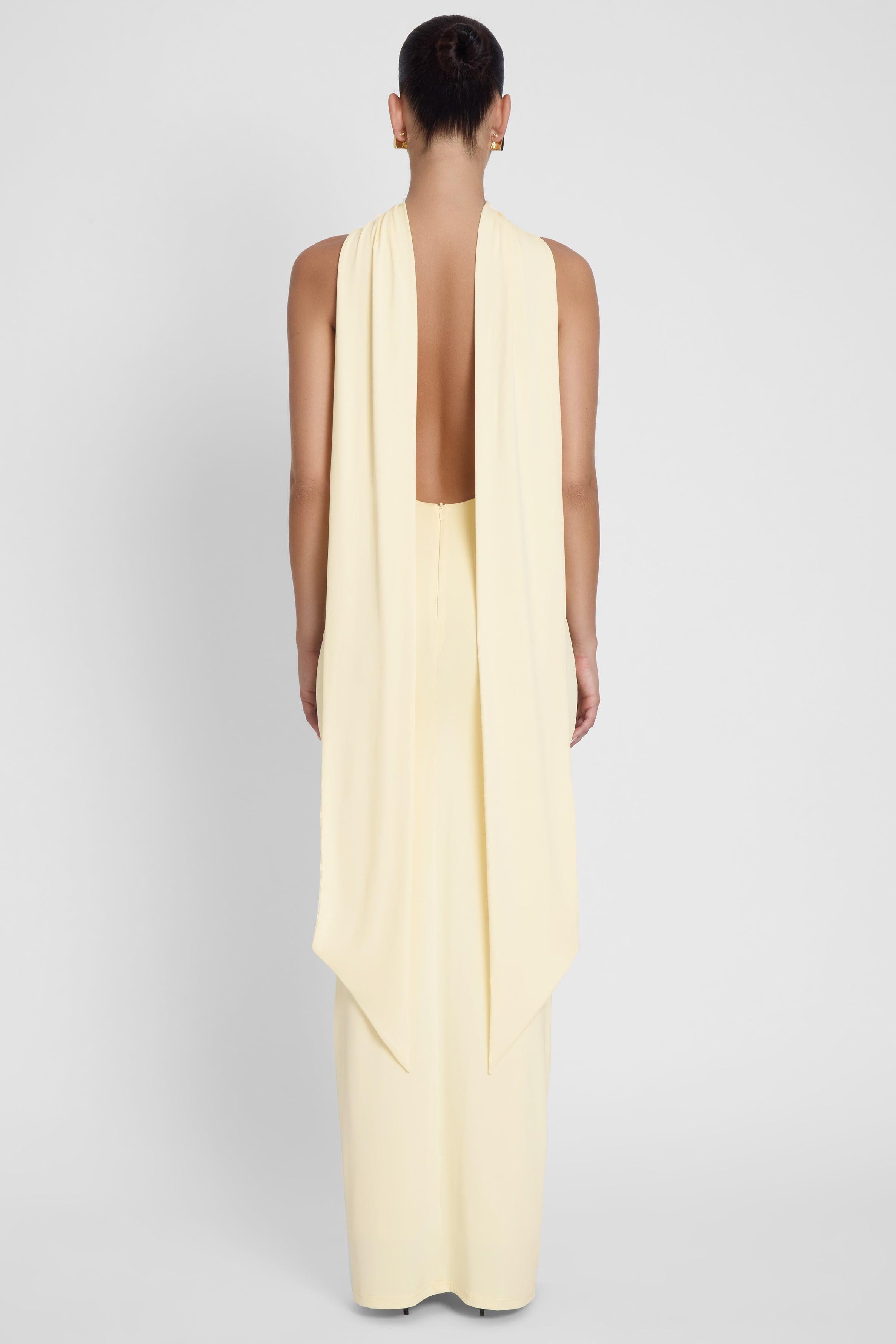 Model is wearing Alaia Drape Maxi Dress Yellow, back view.