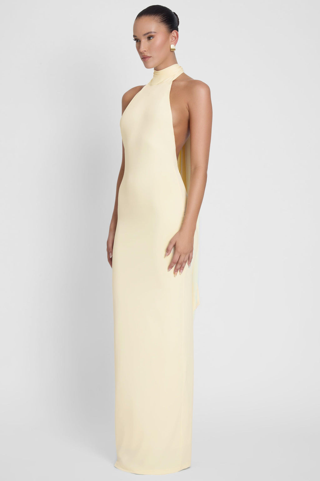 Model is wearing Alaia Drape Maxi Dress Yellow, side view.