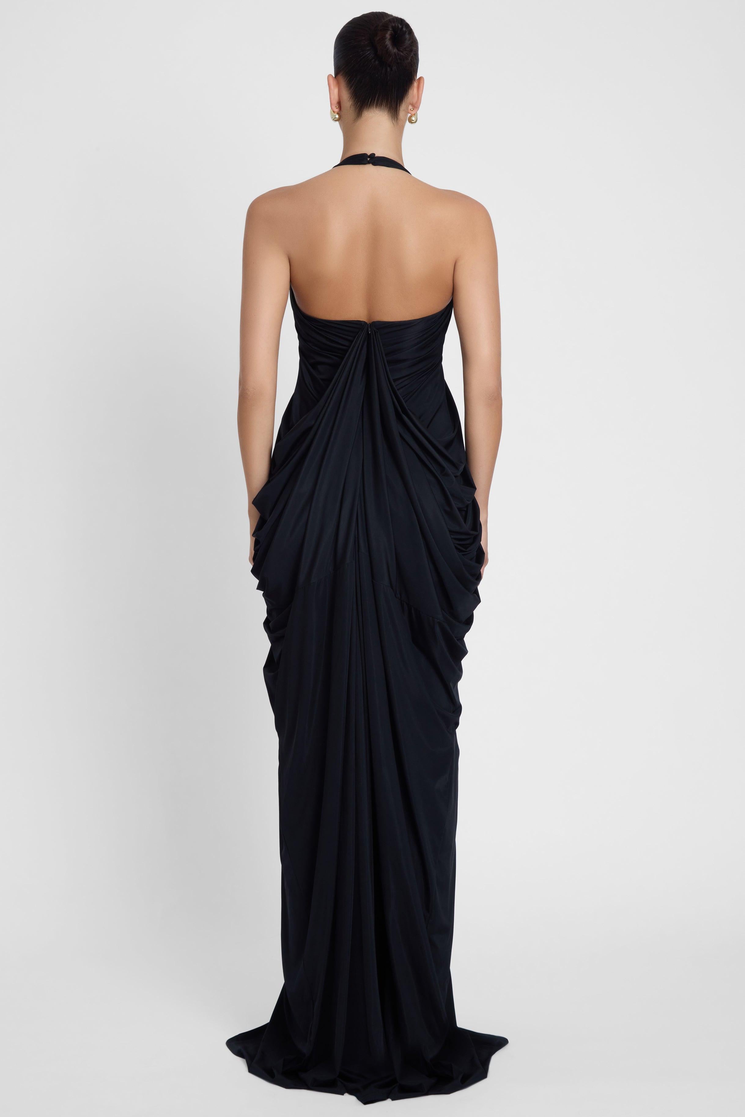 Model is wearing Cascade Drape Gown Black in Black, back view.