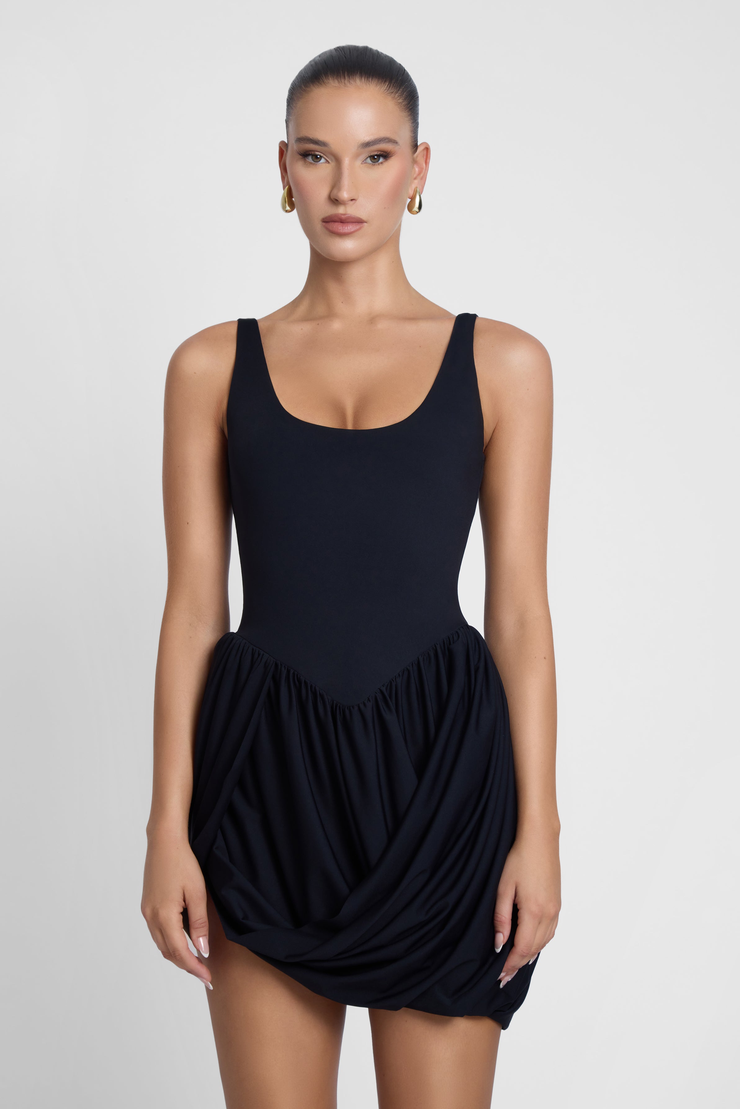 Model is wearing Dasia Sculpt Drape Mini Dress Black, front view.