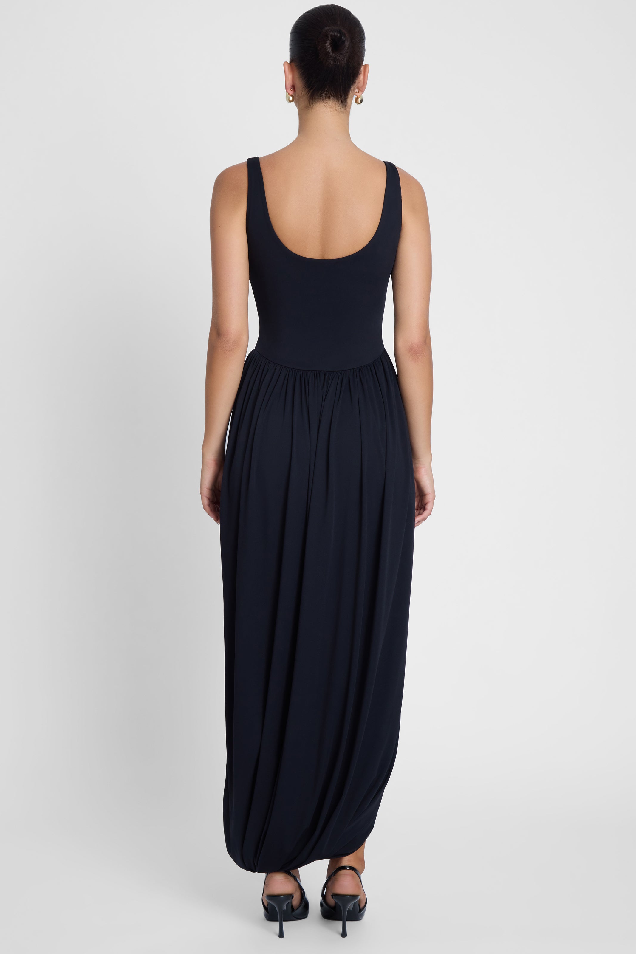Model is wearing Dionysus Sculpt Drape Midi Dress, back view.