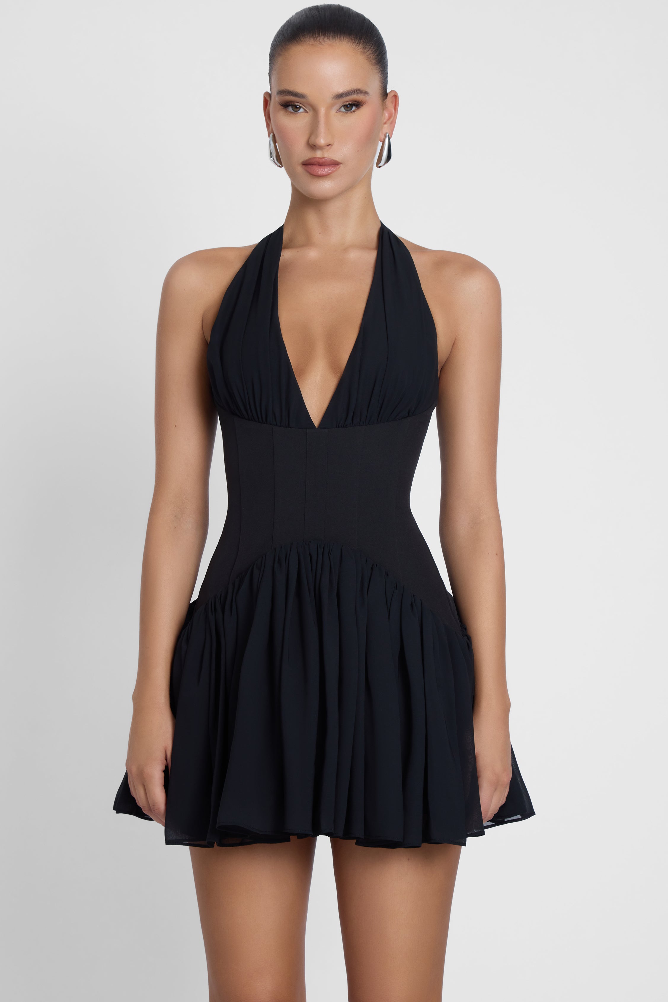 Model is wearing Harper Corset Mini Dress Black, front view.