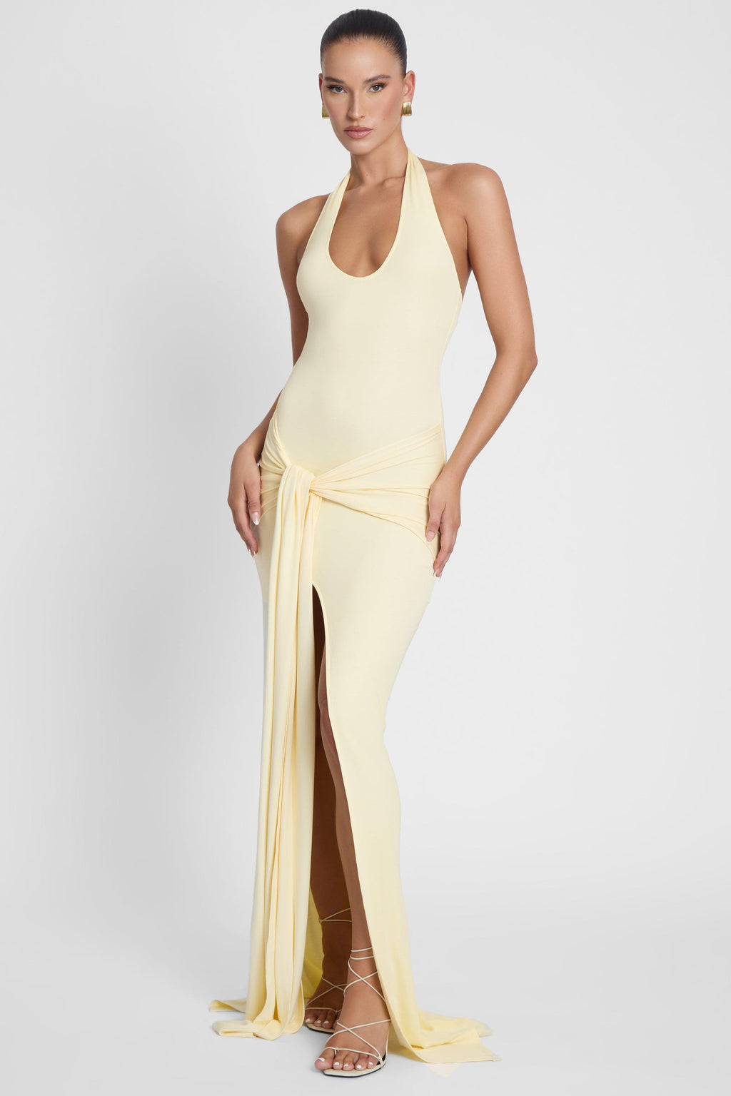 Model is wearing Heaven Halter Jersey Knot Maxi Dress Yellow, side view.
