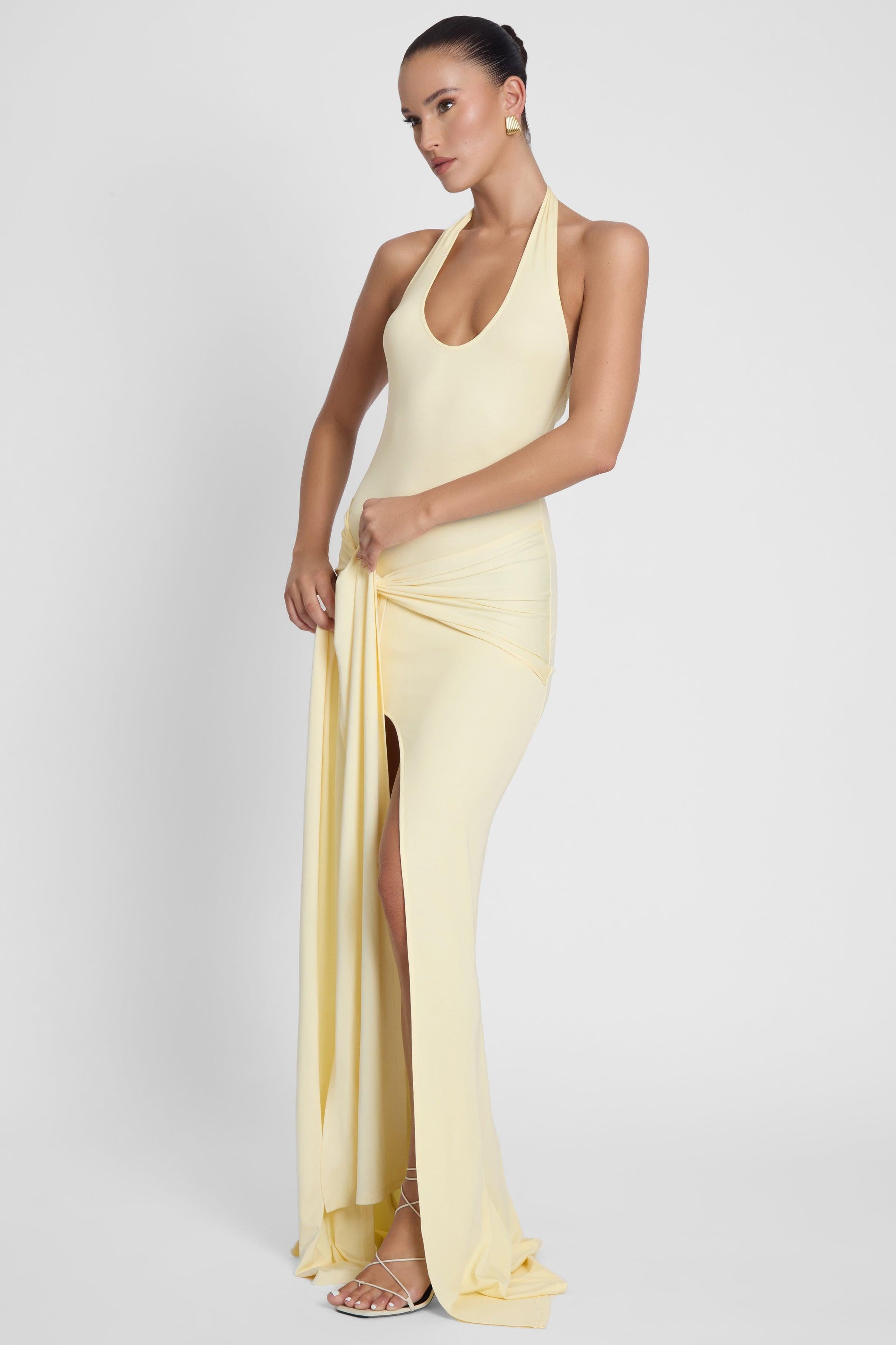 Model is wearing Heaven Halter Jersey Knot Maxi Dress Yellow, side view.